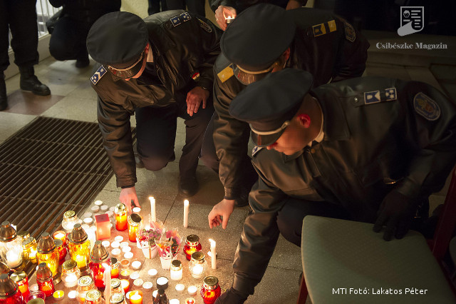 Az elhunyt két kollégájukra emlékező rendőrök mécsest gyújtanak a XVIII. kerületi rendőrkapitányság előtt 2015. február 7-én.